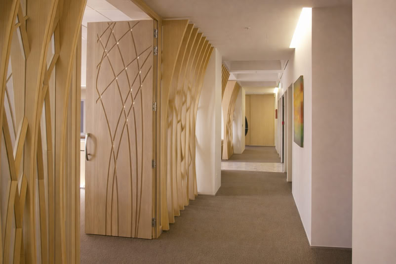 A hallway with decorative wooden panels featuring abstract designs, beige walls, and a carpeted floor.