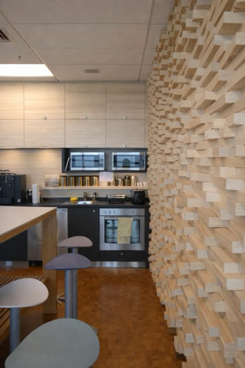 Modern kitchen with a textured wooden wall, stainless steel appliances, and a countertop with bar stools.