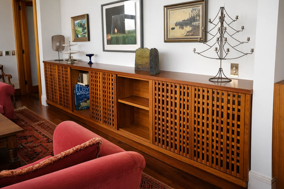 A wooden sideboard with lattice doors, decorative items on top, and framed artwork on the wall above.
