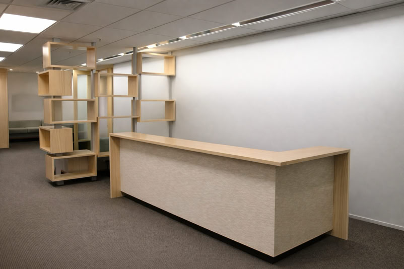 Room with a long wooden counter and wooden shelving units against a white wall.